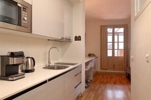 A modern kitchen with a microwave, coffee maker, and stainless steel sink.