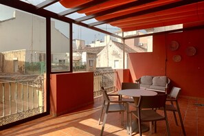 A balcony with a table and chairs, a view of the cityscape, and a red wall with decorative plates. - Thyssen Terrace Apartment (Málaga)