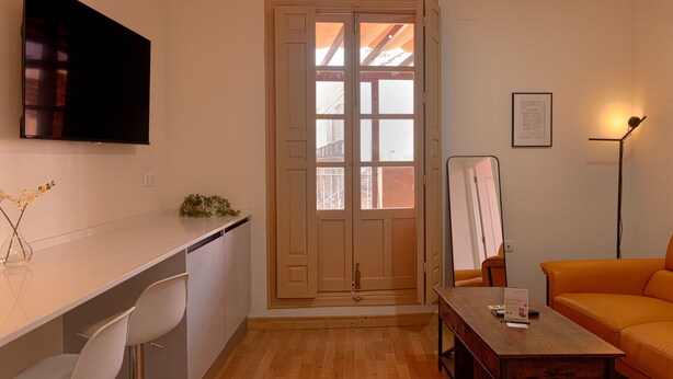 Un espacio habitable compacto con kitchenette, zona de comedor y sala de estar con sofá.