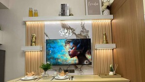 Un espace repas moderne comprenant un bureau en bois, deux chaises, un téléviseur et des objets décoratifs.