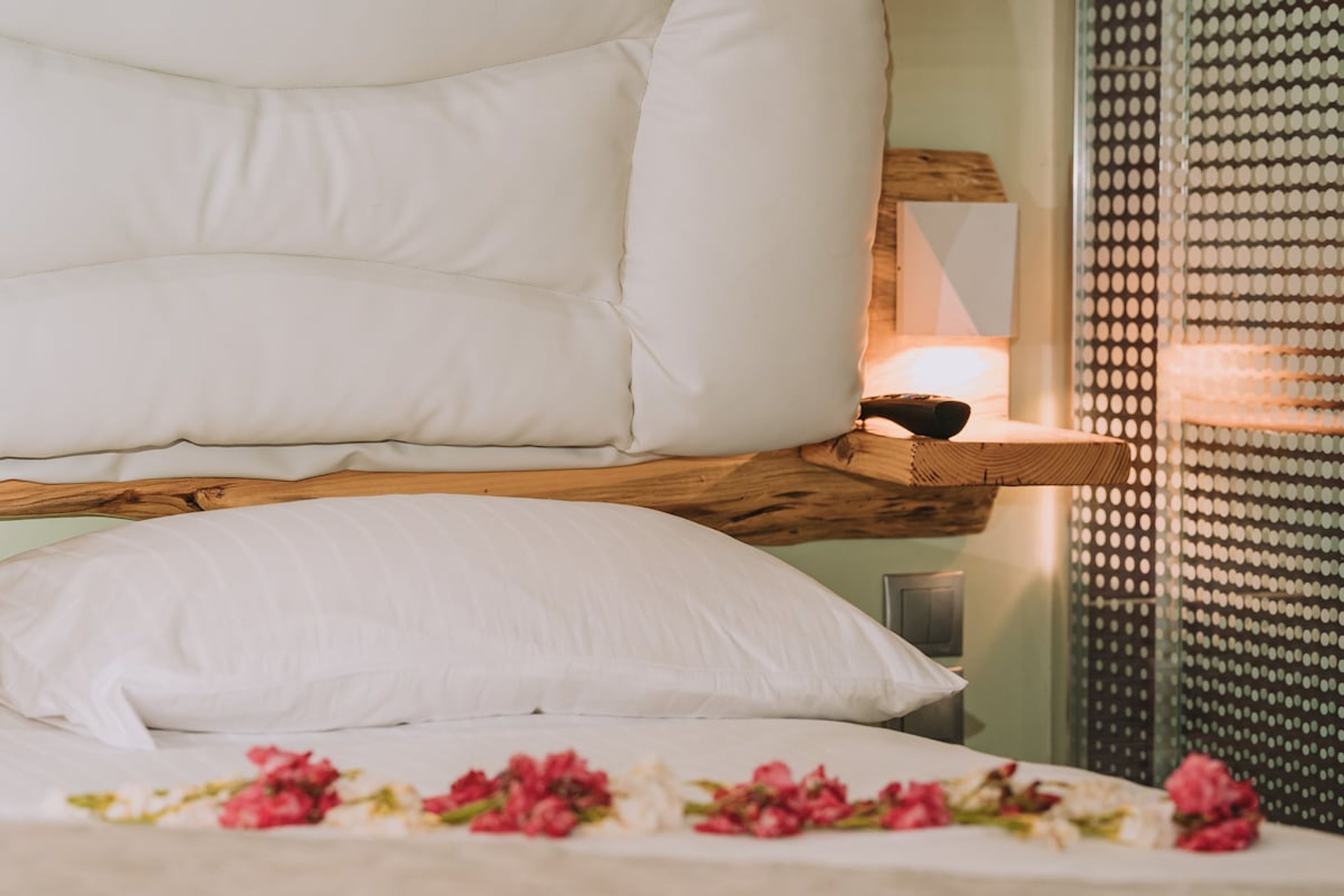 Una cama con ropa blanca y cabecera de madera.