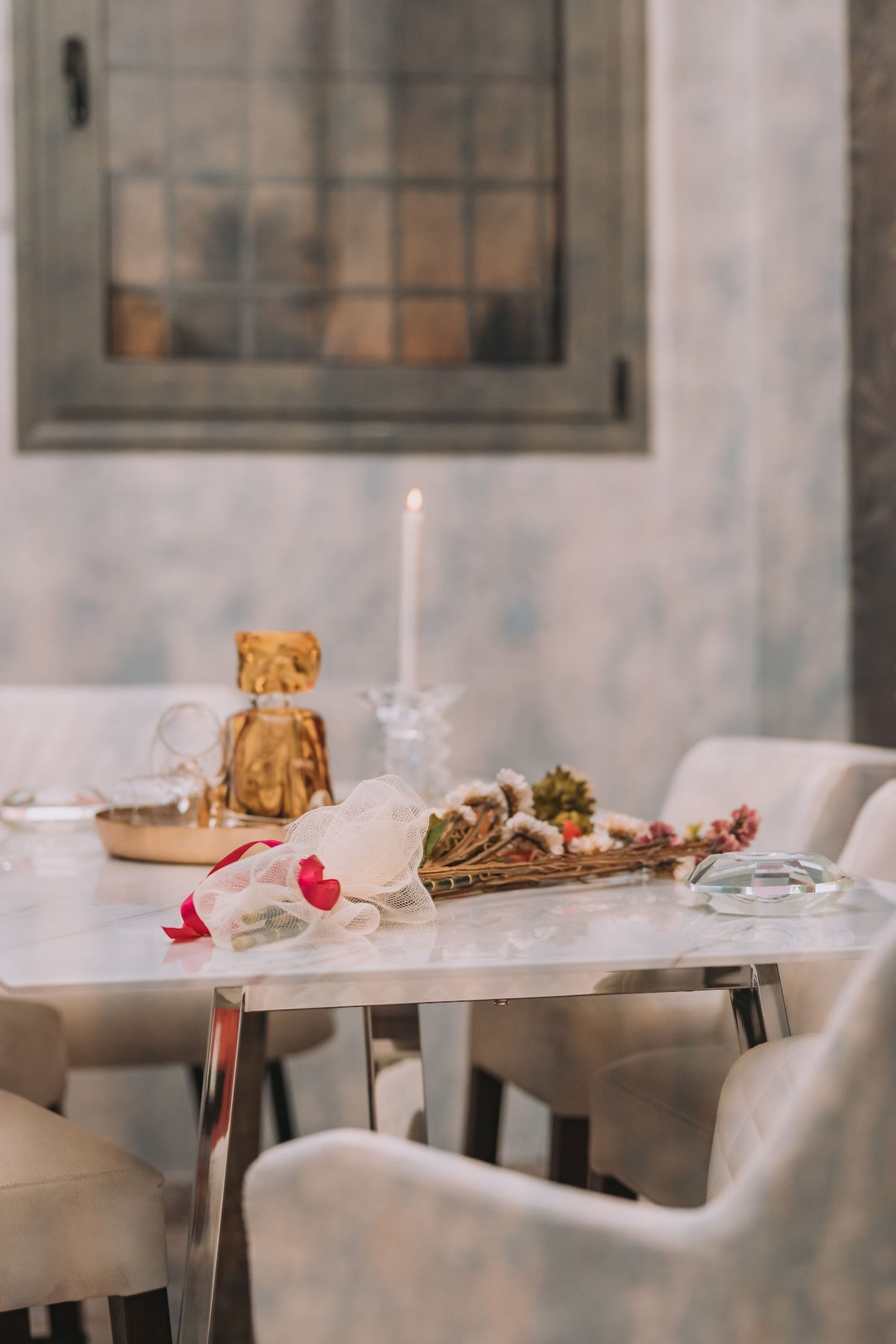 Una mesa de comedor con una vela, un llavero y un arreglo decorativo.
