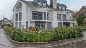 A modern two-story house with a balcony, a garage, and a well-maintained garden.