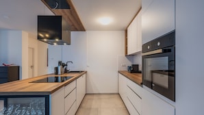 A modern kitchen with a wooden countertop, stainless steel appliances, and a glass wine cooler.