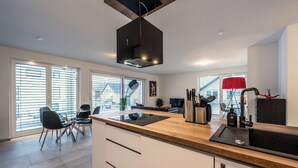 A modern kitchen with a central island, built-in appliances, and a dining area with a table and chairs.