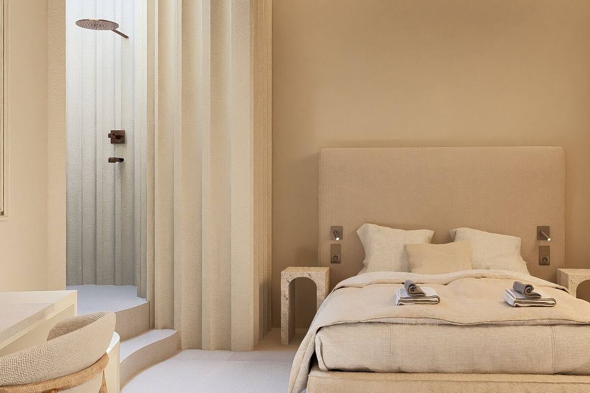 A hotel room with a large bed, a bathroom with a shower, and a small seating area.