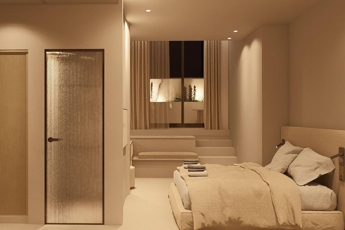 A bedroom with a large bed, a wardrobe, and a staircase leading to an upper level.