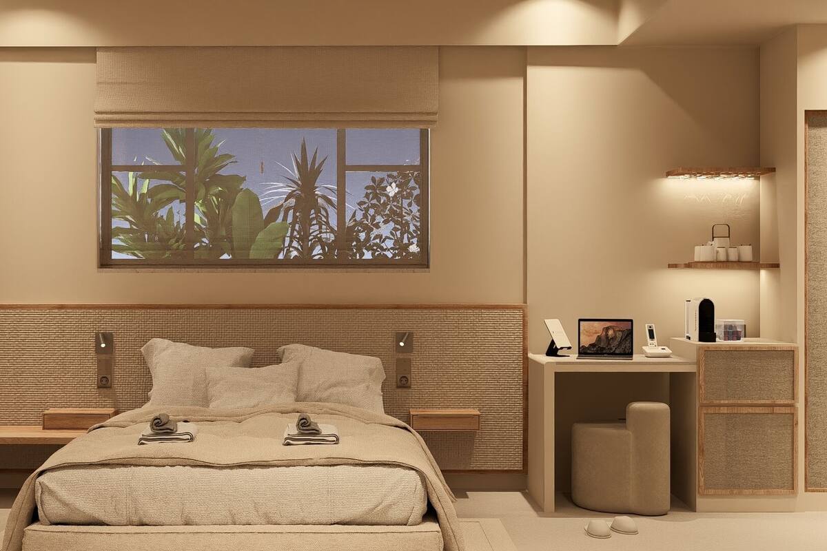 A modern bedroom with a large bed, bedside tables, a desk with a chair, a window with a view of palm trees, and a shelf with toiletries.