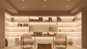 A modern library with multiple shelves of books, two armchairs, and a round coffee table. - F ZEEN ATHENS – Adults Only (Athens)