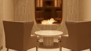 A modern interior with a stone-textured wall, a round stone table, and two leather chairs. - F ZEEN ATHENS – Adults Only (Athens)