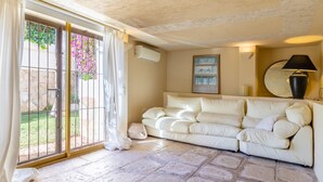 A living room with a beige sofa, a glass door leading outside, and a wall-mounted lamp.