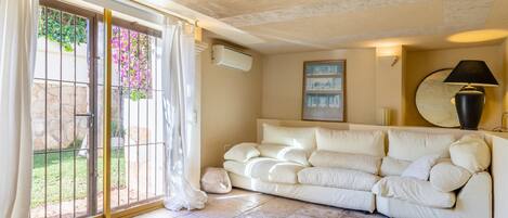 A living room with a beige sofa, a glass door leading outside, and a wall-mounted lamp.