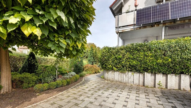 A paved pathway leading to a building with solar panels on the roof.