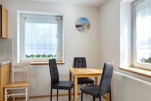 En matplats med ett bord och stolar, ett fönster med persienner och en tavla som hänger på väggen.