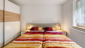 A bedroom with a bed, bedside tables, and a window.