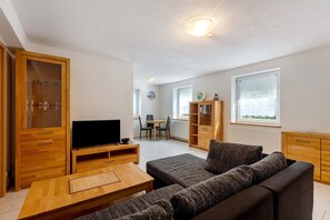 Ett modernt vardagsrum med en soffa, TV, ett träskåp och en matplats.