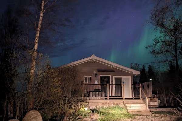 Sunset Cove illuminated under the Northern Lights — the perfect welcome to your lakefront getaway.
