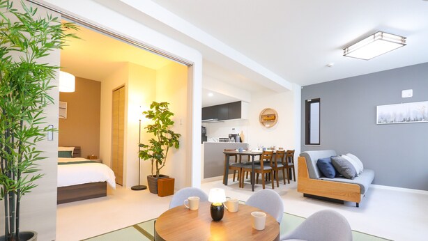 Et moderne hotelværelse med spiseplads, en sofa og et køkken i baggrunden.