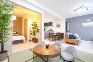 Una habitación de hotel moderna con comedor, sofá y cocina al fondo.