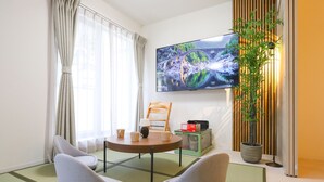 Et moderne værelse med tatamimåtter, fjernsyn, en plante og et traditionelt japansk te-sæt.