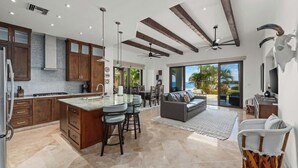 A spacious kitchen with a central island, wooden cabinets, and a dining area with a sofa and chairs. - Luxurious Ocean View Retreat at El Encanto! (San Jose del Cabo)