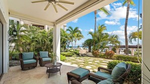 A covered outdoor area with wicker furniture, a ceiling fan, and a view of palm trees and a beach. - Luxurious Ocean View Retreat at El Encanto! (San Jose del Cabo)