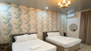 A hotel room with two beds, a chandelier, a round mirror, and a floral wallpaper design. - Leonas By RSM (Tagaytay)