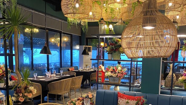 A restaurant with wicker furniture, black tablecloths, and hanging wicker lamps. - Leonas By RSM (Tagaytay)