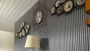 A modern living room with a blue sofa, a blue lamp, and decorative wall clocks. - Leonas By RSM (Tagaytay)