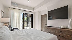 A modern hotel room with a large bed, a flat-screen TV mounted on the wall, a wooden dresser, and a sliding glass door leading to a balcony. - Edge Of Powder | Includes Two 1-Day Lift Tickets (Tamarack)