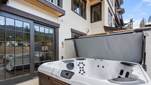 A hot tub with a control panel, a wooden bench, and a glass door leading to a balcony. - Edge Of Powder | Includes Two 1-Day Lift Tickets (Tamarack)