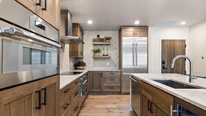 A modern kitchen with wooden cabinets, stainless steel appliances, and a central island. - Edge Of Powder | Includes Two 1-Day Lift Tickets (Tamarack)