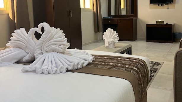 A hotel room with a large bed, a wardrobe, a television, and a mirror. - Rest inn (Madinah)
