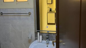 A bathroom with a white sink, a mirror, and a window with frosted glass panels. - Rest inn (Madinah)
