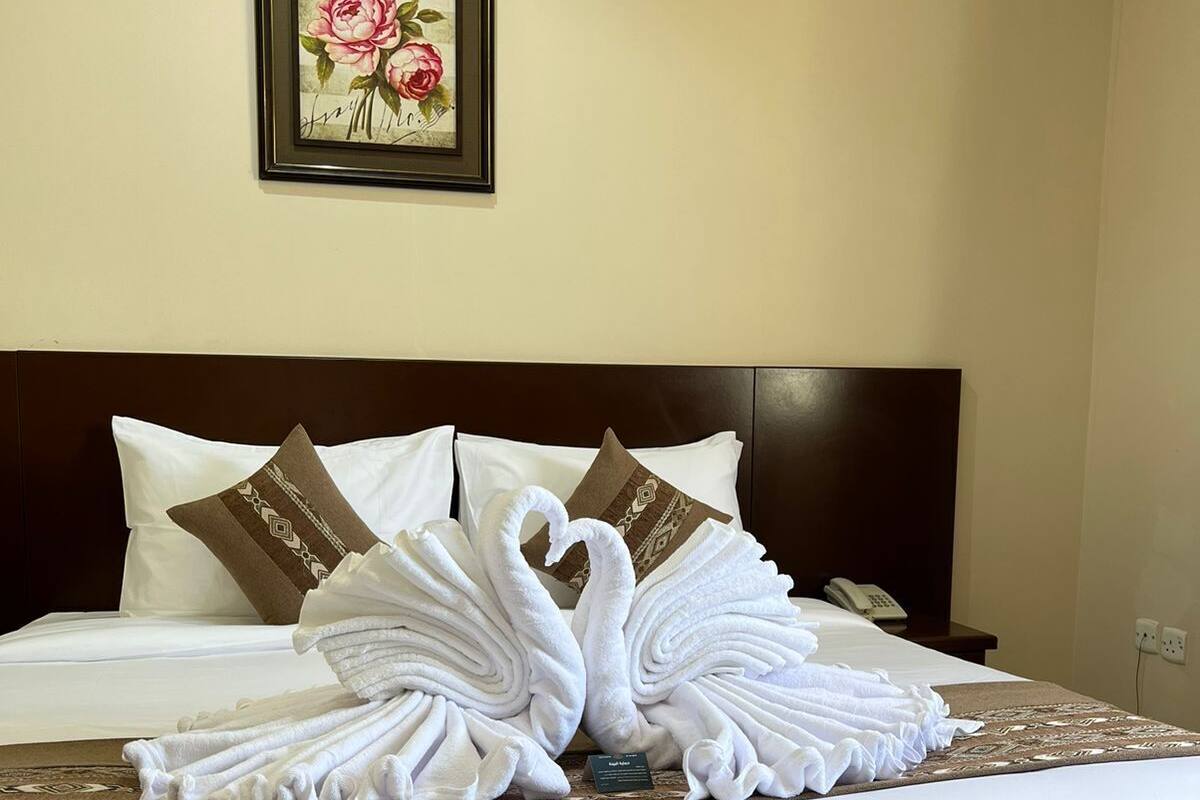 Une chambre d’hôtel avec un lit soigneusement fait, une œuvre d’art florale encadrée accrochée au mur et un téléphone sur la table de chevet.