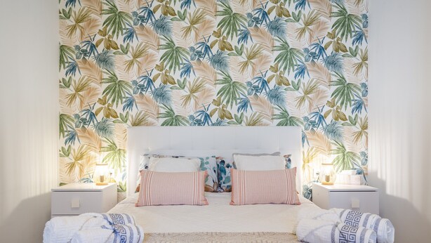 A bedroom with a patterned wall, a bed with pillows, and two bedside tables with lamps. - Charming Holiday Home 'Can Dornena Refugio' with Mountain View, Wi-Fi & Air Conditioning (Maçanet de la Selva)