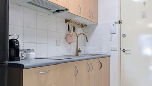 Cozinha com armários de madeira, pia de aço inoxidável e cafeteira.