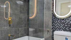 Casa de banho moderna com chuveiro em cabine de vidro, lavatório branco e sanita com etiqueta de classificação de consumo de água.