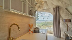 Cozinha moderna com uma grande janela, vista para o campo e um design de teto geométrico exclusivo.