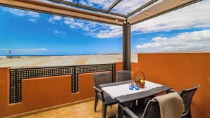 A covered outdoor seating area with a table and chairs, a basket of fruit, and a view of the landscape. - Sotavento Horizon Views Suite (La Tejita)