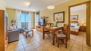 A well-lit room with a dining table, chairs, a sofa, and a bed. - Sotavento Horizon Views Suite (La Tejita)