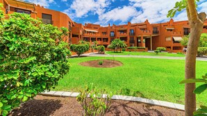 A courtyard with a central lawn, surrounded by buildings with balconies and windows. - Sotavento Horizon Views Suite (La Tejita)