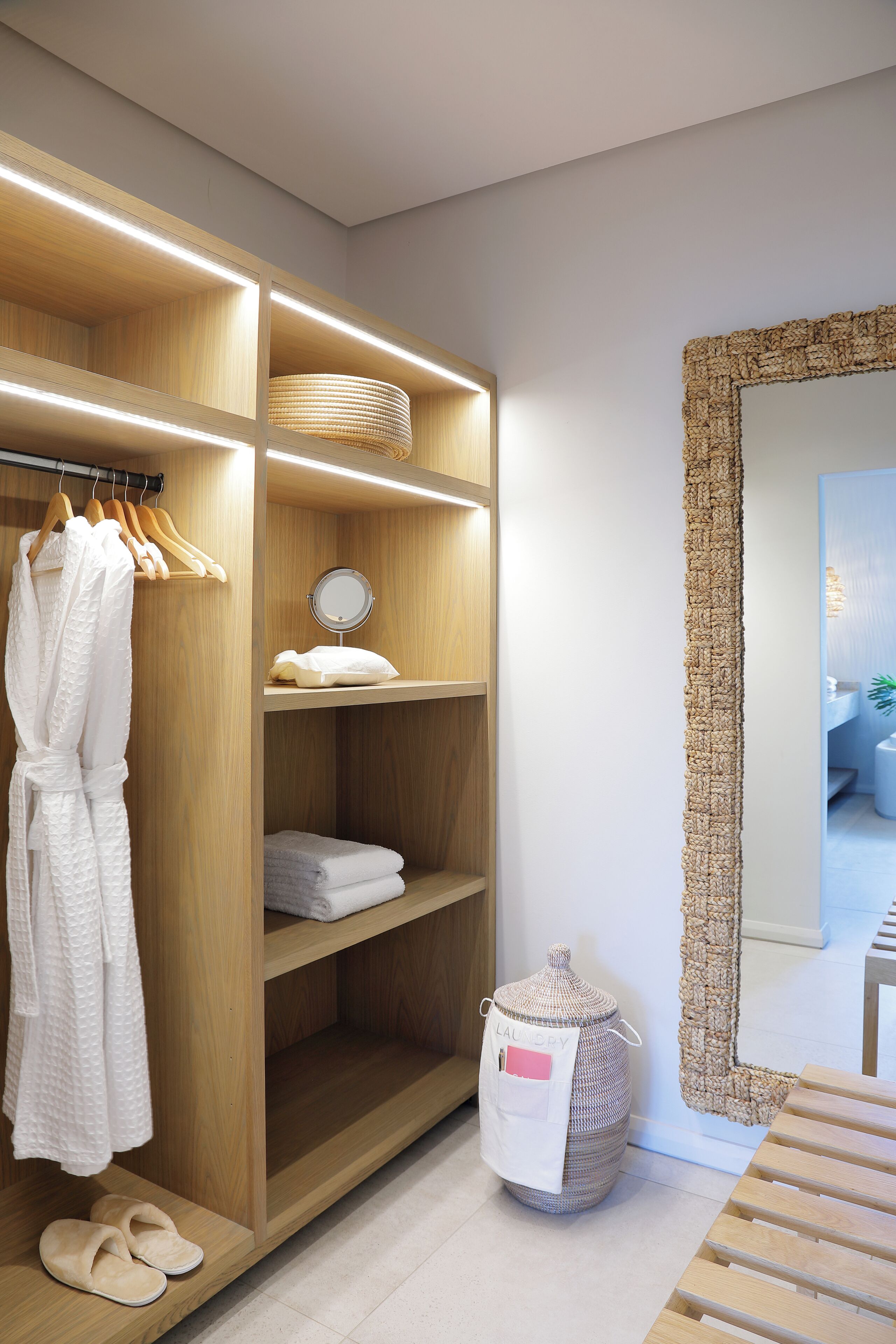 A modern bathroom with a wooden vanity, a round mirror, and a large mirror with a textured frame.