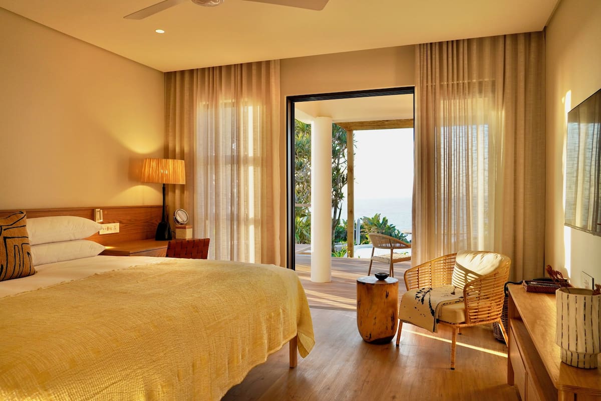 A hotel room with a large bed, a desk, a chair, and a view of the outdoors.