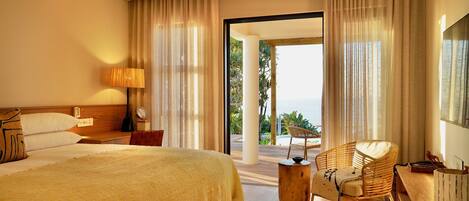 A hotel room with a large bed, a desk, a chair, and a view of the outdoors.