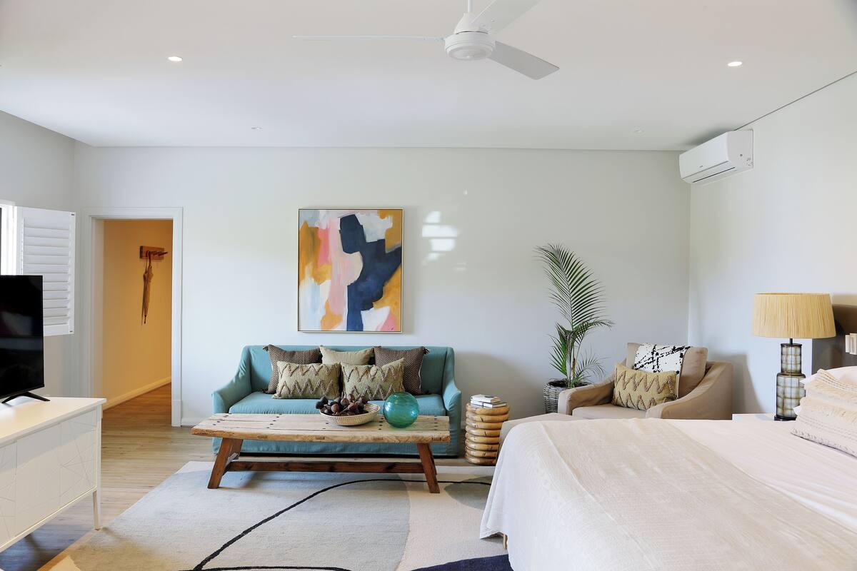 A modern living room with a sofa, coffee table, and a bed.