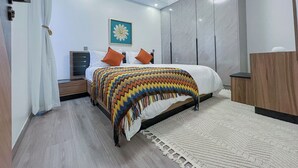 Une chambre à coucher moderne, avec un lit, une table de chevet, une commode, une grande fenêtre et un luminaire au plafond.