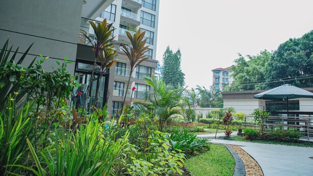Un bâtiment moderne doté de balcons, entouré d’une végétation luxuriante et agrémenté d’un jardin bien entretenu.