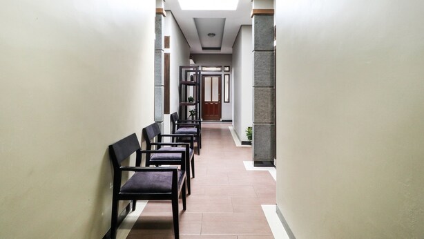 A hallway with chairs lined up, a door at the end, and a ceiling light. - Hotel O Guest House Teras Waruga Syariah (Parongpong)