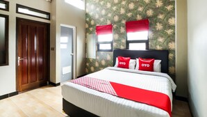 A hotel room with a bed, a wardrobe, a window with red curtains, and a wall with a leafy pattern. - Hotel O Guest House Teras Waruga Syariah (Parongpong)
